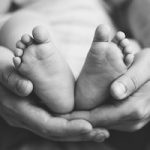 Closeup Shot Of A Baby's Feet Held In His Father's Hands